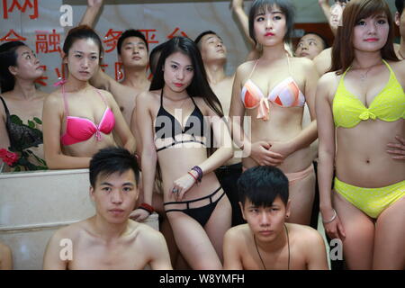 Chinesische Mitarbeiter gekleidet in Bikinis und Badehosen den Eimer für das Eis Herausforderung Boykott in ihrem Büro in Shenzhen City, South China Guan Stockfoto