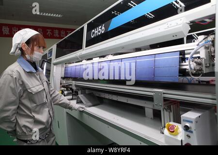 ---- Eine weibliche chinesischer Arbeiter überwacht die Produktion von Solarzellen von Solarzellen im Werk Shanghai Shenzhou New Energy Development Co. Stockfoto