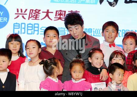 Chinesische Pianist Lang Lang, hinten Mitte, macht ein Gesicht, ein kleines Mädchen, als er mit kleinen Kindern während einer Pressekonferenz für die Shenyang Konzert o Stellt Stockfoto