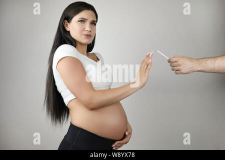 Brünette junge schwangere Frau ablehnen, Zigarette auf isolierten weißen Hintergrund zu rauchen Stockfoto