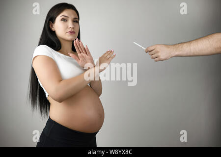 Brunette schöne schwangere Frau ablehnen, Zigarette auf isolierten weißen Hintergrund zu rauchen Stockfoto