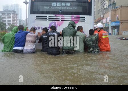 Anwohner push ein Bus auf einer überfluteten Straße durch Unwetter in Guiyang city verursacht, der Südwesten Chinas Provinz Guizhou, 15. Juli 2014. Schwere Regenfälle haben Stockfoto