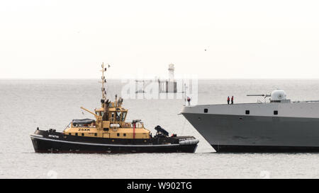 Ein Schubschiff unterstützt die SAS AMATOLA von Simons Town Flottenstützpunkt auf Südafrika der False Bay Küste in der Nähe von Kapstadt Stockfoto