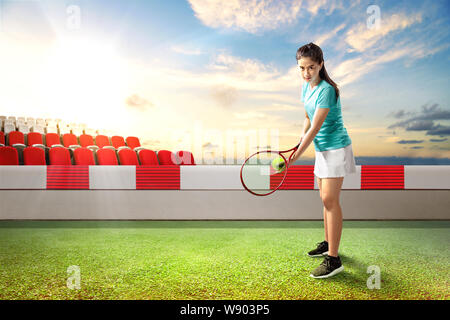 Asiatische Frau mit Tennisschläger und Ball in ihre Hände in die Position auf dem Tennisplatz im Freien bereit Stockfoto