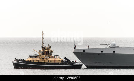 Ein Schubschiff unterstützt die SAS AMATOLA von Simons Town Flottenstützpunkt auf Südafrika der False Bay Küste in der Nähe von Kapstadt Stockfoto