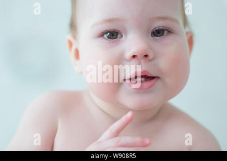 Little Baby Junge Mädchen 7-8 Monate zeigt die ersten beiden Zähne, Porträt Gesicht des Babys. Zahnende Baby Milch Zähne kleines Kind Portrait in Stockfoto