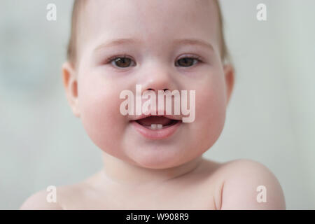 Baby 6-7 Monate lächelnd zeigt erste Zähne, Baby Gesicht Nahaufnahme Porträt. Pretty baby girl Boy geschwollene Wangen. Kind Kleinkind makro Gesichtszüge Stockfoto