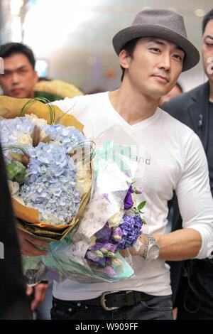Koreanische Schauspieler Song Seung-heon hält Blumensträuße, während er an der Klemme der Beijing Capital International Flughafen nach der Ankunft i Stockfoto