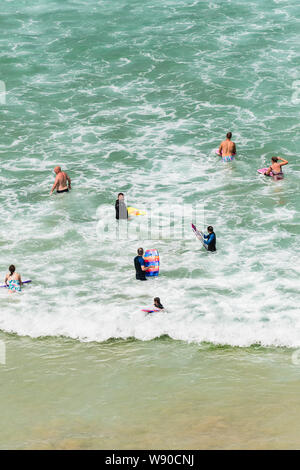 Urlauber in das Meer und die Abkühlung der heißen Sommer Wetter im Great Western Beach in Newquay in Cornwall. Stockfoto