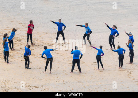 Unerfahrene surfer Aufwärmen vor einer surflektion am Großen Gt. Western Beach in Newquay in Cornwall. Stockfoto