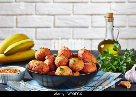 Close-up frittierte Kochbanane Krapfen Klako in einem schwarzen Schüssel mit Zutaten und die Mauer im Hintergrund, afrikanische Küche, horizontale Ansicht Stockfoto