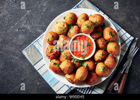 Wegerich Krapfen Klako auf einer weißen Platte mit Hot Sauce serviert, vegan Beilage, Street Food, afrikanische Küche, Ansicht von oben, flatlay, kopieren Raum Stockfoto