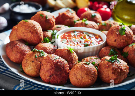 Close-up frittierte Kochbanane Krapfen Klako auf einem weißen Teller mit Paprika und Tomaten Sauce, afrikanische Küche, horizontale Ansicht Stockfoto