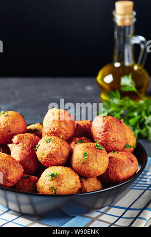 Close-up frittierte Kochbanane Kroketten Klako in einem schwarzen Schüssel mit Zutaten auf dem schwarzen Hintergrund, afrikanische Küche, vertikale Ansicht Stockfoto