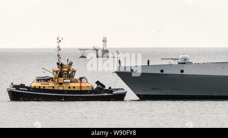 Ein Schubschiff unterstützt die SAS AMATOLA von Simons Town Flottenstützpunkt auf Südafrika der False Bay Küste in der Nähe von Kapstadt Stockfoto