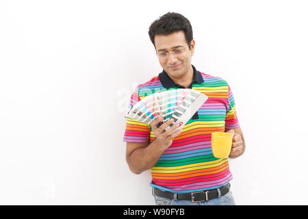 Reifen Mann an Farbmustern und Holding Tasse Kaffee suchen Stockfoto