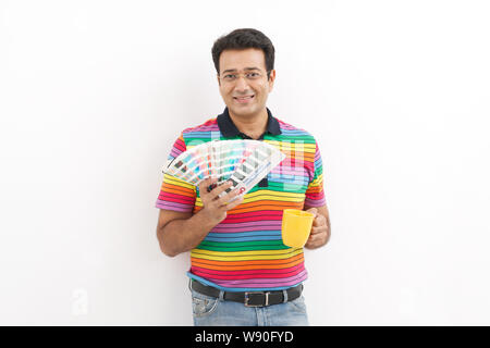 Reifer Mann hält Farbproben und hält Tasse Kaffee Stockfoto