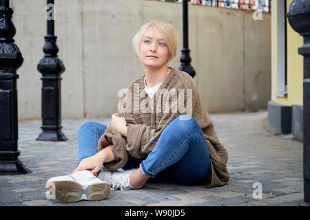 Blond lustig hübsches Mädchen auf Pflaster im zentralen Teil der antiken Stadt. Spaziergang in der Innenstadt. Portrait von Mädchen auf der Straße Stockfoto
