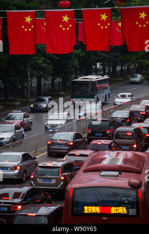 Massen von Fahrzeugen bewegen sich langsam in einem Stau an einer Straße mit chinesischen nationalen Flaggen dekorierte der Nationale Tag Urlaub in Shenzhen City zu feiern. Stockfoto