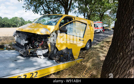 Zahrenholz, Deutschland. 12 Aug, 2019. Eine Deutsche Post Fahrzeug entfernt auf einer Landstraße in der gifhorn Bezirk geschleppt, nachdem das Fahrzeug in einen Baum in einer Biegung am Morgen abgestürzt. Nach Angaben der Polizei, der postbote an der Medizinischen Hochschule Hannover (MHH) in einem Rettungshubschrauber eingetroffen. Credit: Julian Stratenschulte/dpa/Alamy leben Nachrichten Stockfoto