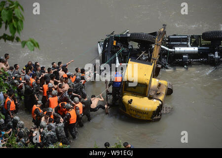 Feuerwehrleute und lokale Leute versuchen für Überlebende in ein militärisches Fahrzeug in einen Fluss auf dem Weg zum Erdbeben in Lushan Grafschaft fiel zu suchen. Stockfoto