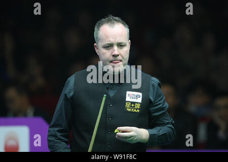 John Higgins von Schottland klebt er seine Zunge heraus, als er einen Schuß gegen Joe Swail in Nordirland in der ersten Runde der 2013 Wor Stockfoto