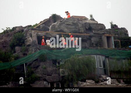 Chinesische Arbeiter tear down the Rock Garden an der Bergspitze Villa, die von Professor Zhang Beiqing auf dem Dach seines Wohnhauses eingebaut ist Stockfoto