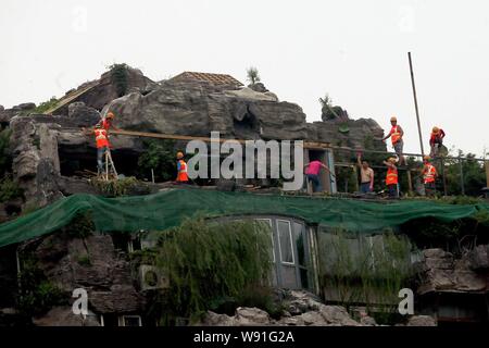 Chinesische Arbeiter tear down the Rock Garden an der Bergspitze Villa, die von Professor Zhang Beiqing auf dem Dach seines Wohnhauses eingebaut ist Stockfoto