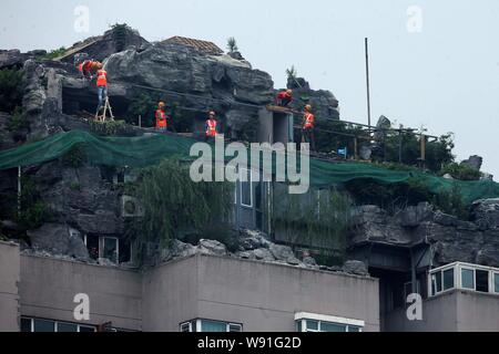 Chinesische Arbeiter tear down the Rock Garden an der Bergspitze Villa, die von Professor Zhang Beiqing auf dem Dach seines Wohnhauses eingebaut ist Stockfoto