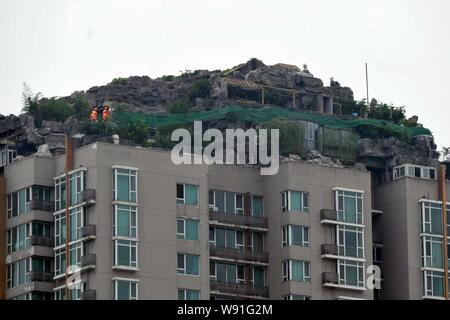 Chinesische Arbeiter tear down the Rock Garden an der Bergspitze Villa, die von Professor Zhang Beiqing auf dem Dach seines Wohnhauses eingebaut ist Stockfoto