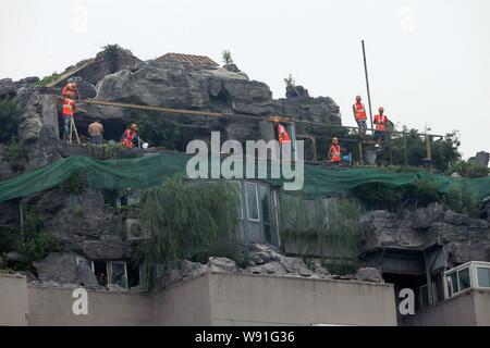 Chinesische Arbeiter tear down the Rock Garden an der Bergspitze Villa, die von Professor Zhang Beiqing auf dem Dach seines Wohnhauses eingebaut ist Stockfoto