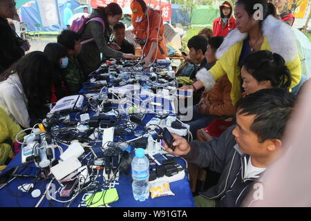 Arbeitnehmer können lokale Bewohner ihre Mobiltelefone, Batterien an einem mobile Ladestation zum Aufladen nach dem 7,0-Erdbeben in Lushan c Stockfoto