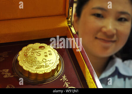 ---- Eine chinesische Angestellte zeigt eine Gold mooncake an einem gold Shop in Handan Stadt, North China Provinz Hebei, 22. August 2013. China hat Beamte verboten Stockfoto