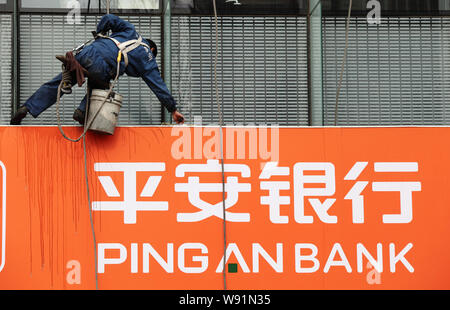 ---- Ein chinesischer Arbeiter reinigt die Tafel von einem Zweig von Ping eine Bank in Peking, China, 17. April 2013. Die Ping An Insurance Group Co von China Stockfoto