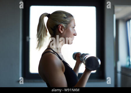 Junge Frau im Fitnesscenter mit Hanteln Kraft und Kraftausdauer Stockfoto