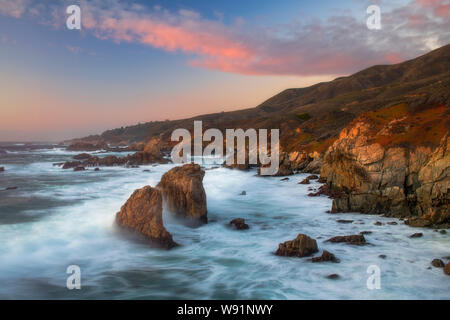 Sonnenaufgang und Wellen entlang der zerklüfteten Küste von Big Sur in Kalifornien, Monterey County, Kalifornien Stockfoto