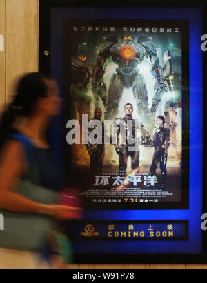 ---- Eine chinesische Kinogänger Spaziergänge hinter einem Plakat des Films, Pacific Rim, in einem Kino in Kunshan City, Central China Provinz Hubei, 30. Juli 2013. Stockfoto