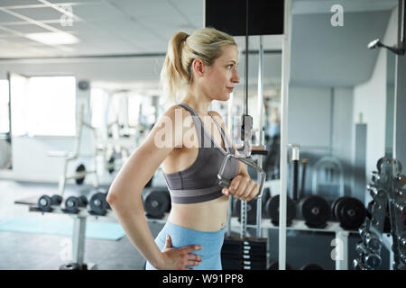 Frau tun, Fitness- und Krafttraining für den Trizeps auf dem Kabel im Fitnesscenter Stockfoto