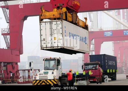 Ein Kran Fahrzeug entlädt einen Behälter mit Sinotrans im Ausland von einem Lkw im Hafen von Qingdao in Qingdao Stadt versendet werden, East China Shandong provin Stockfoto