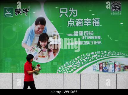 ---- Einen Fußgänger an eine Werbung von Mengniu Dairy in Kunshan, China Provinz Hubei, 15. Juli 2013. Die Inner-Mongolia-basierten Stockfoto
