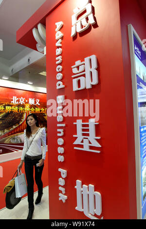---- Eine trendige junge chinesische Frau geht hinter dem Stand der Advanced Business Park (ABP) während einer Ausstellung in Peking, China, 6. November 2010. Ein Stockfoto