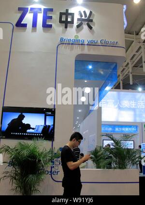 ---- Ein chinesischer Besucher sucht bei seinem Telefon am Stand von ZTE während der Expo in Nanjing, China, Provinz Jiangsu, 6. September 2012. Apple im Stockfoto