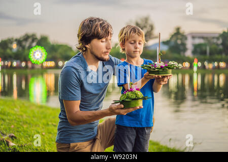 Vater und Sohn Touristen hält die Loy Krathong in ihren Händen und es geht um in das Wasser zu starten. Loy Krathong Festival, die Menschen kaufen Blumen und Stockfoto