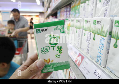 ---- Ein Kunde kauft einen Kasten von Mengniu Milch in einem Supermarkt in Xuchang, Zentrale China Provinz Henan, 22. Juni 2013. Chinesischen staatseigenen conglome Stockfoto