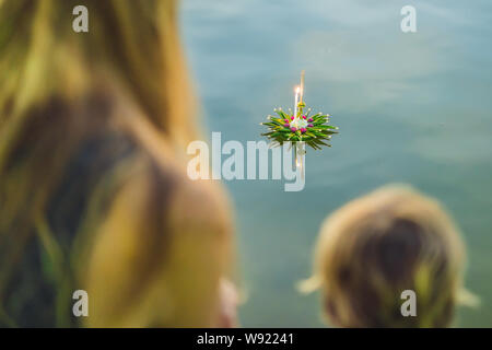 Mutter und Sohn Touristen hält die Loy Krathong in ihren Händen und es geht um in das Wasser zu starten. Loy Krathong Festival, die Menschen kaufen Blumen und Stockfoto