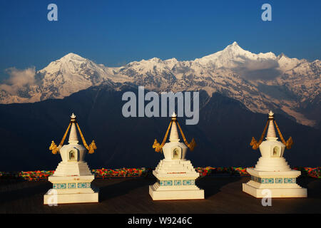 Tibetischen stupas gesehen werden, wenn die ersten Sonnenstrahlen den Kawagebo Peak bei Meili Snow Mountain in Shigatse Grafschaft schlagen, Nordosten China Yunnan Provinz, 3 Stockfoto