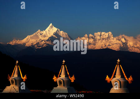 Tibetischen stupas gesehen werden, wenn die ersten Sonnenstrahlen den Kawagebo Peak bei Meili Snow Mountain in Shigatse Grafschaft schlagen, Nordosten China Yunnan Provinz, 3 Stockfoto