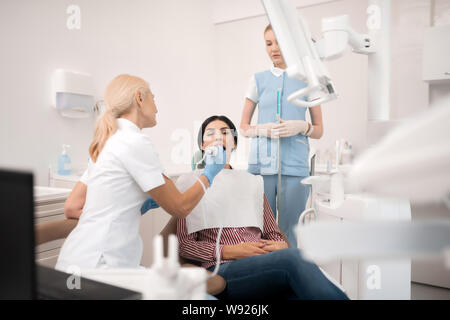 Zahnarzt und ihre Assistentin der Betreuung ihrer Patienten. Stockfoto