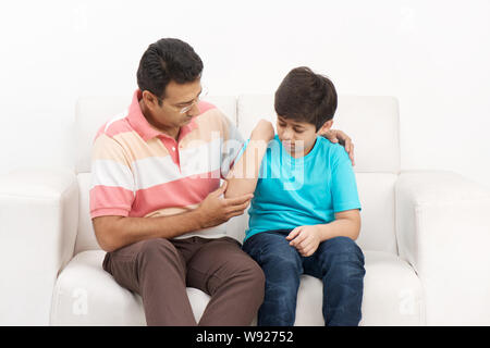 Mann legt Verband auf Sohn, s Hand Stockfoto