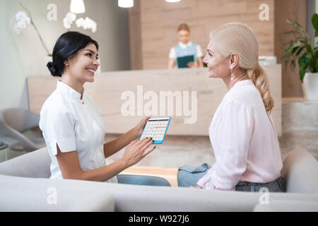 Frau im Gespräch mit Ihrem Zahnarzt über den nächsten Besuch. Stockfoto